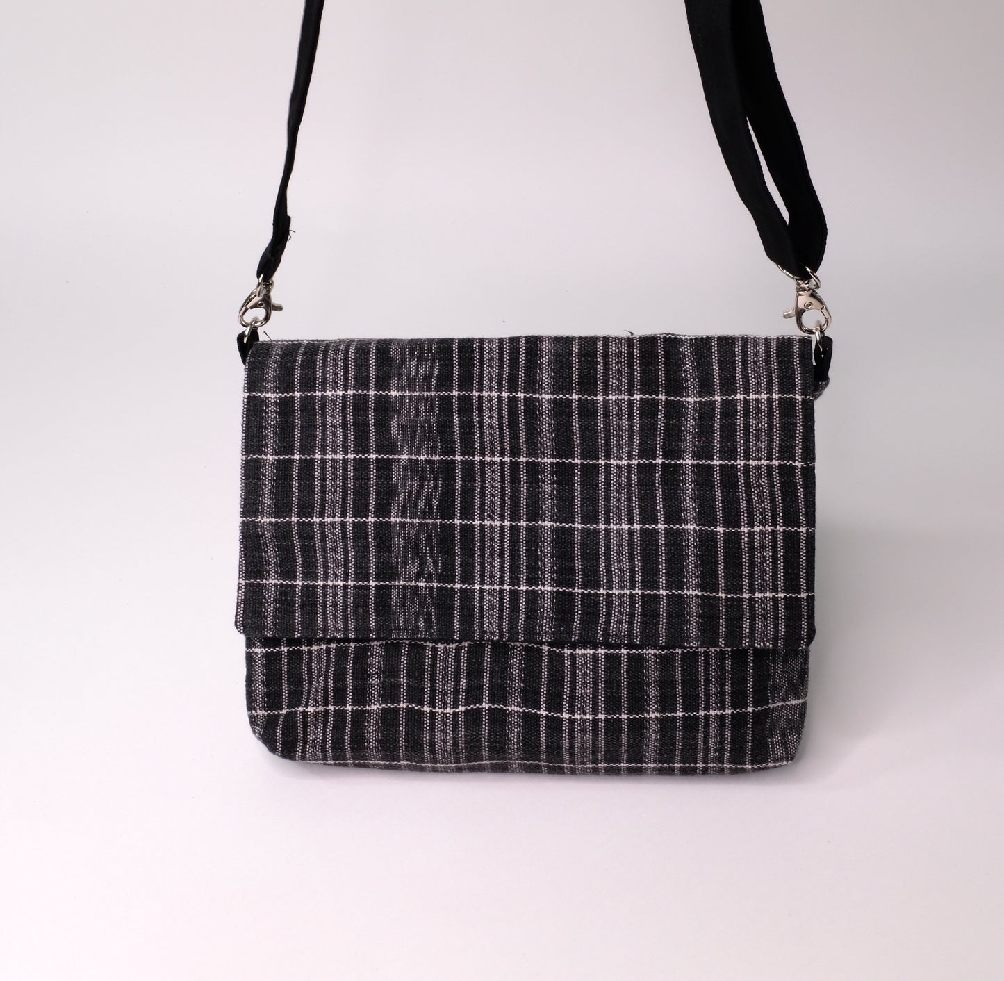 Crossbody bag is constructed with carefully handwoven black ikat cotton textiles.