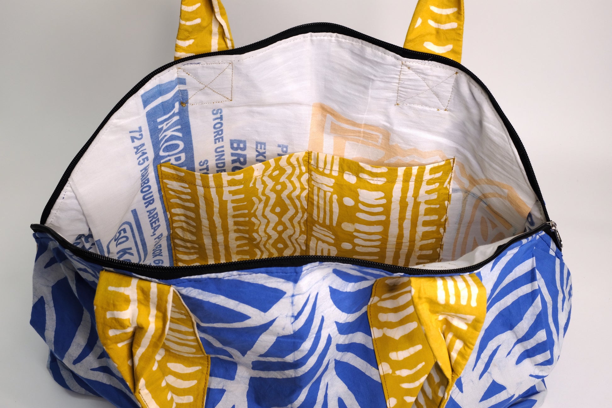 Large zippered weekend bag with a blue plant pattern and yellow straps.