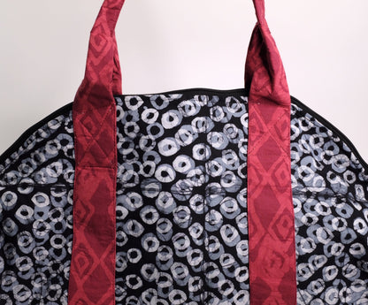 Larger zippered weekend bag with a black ring pattern with red straps.