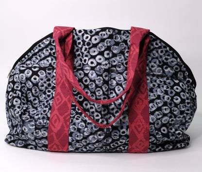 Larger zippered weekend bag with a black ring pattern with red straps.